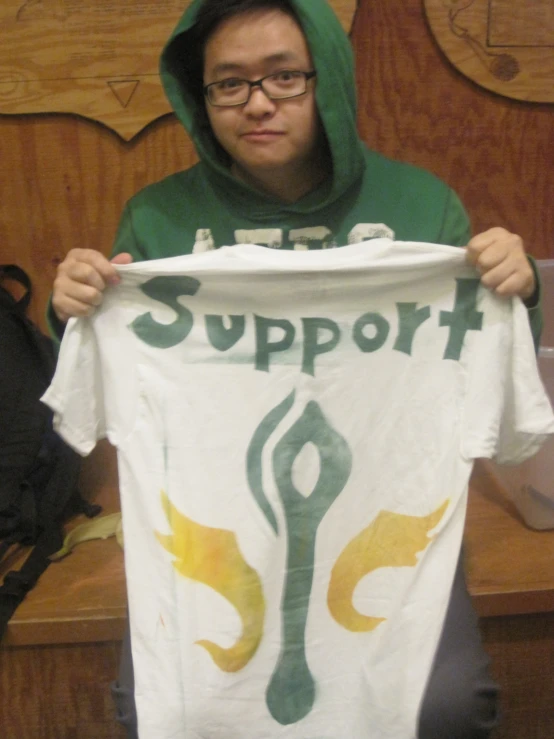 a young man holding a white t - shirt that reads support