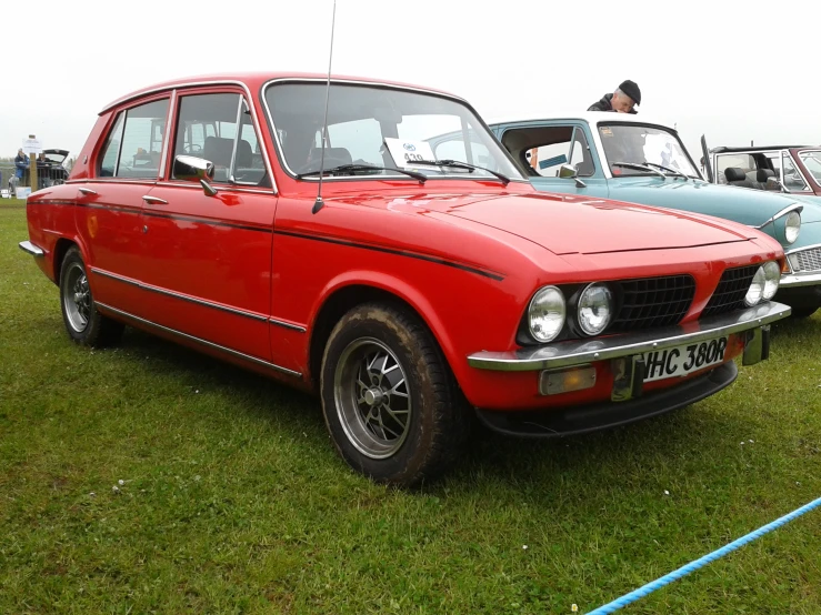 two cars on the grass one red and one blue