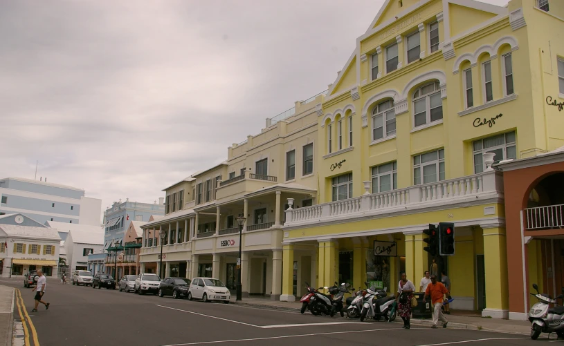 a city street with lots of yellow buildings and motorcycles parked along it