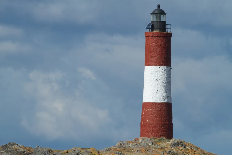 a white and red lighthouse on a hill