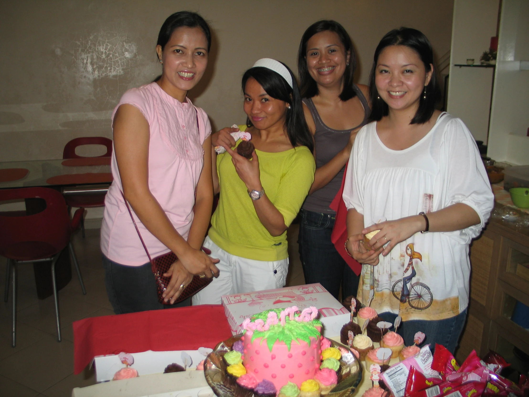 four women posing for a po in front of a birthday cake