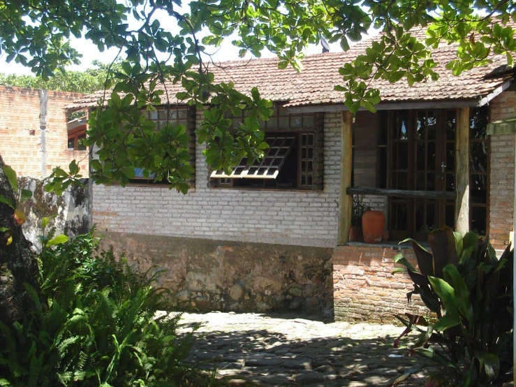 a brick house that is sitting under trees