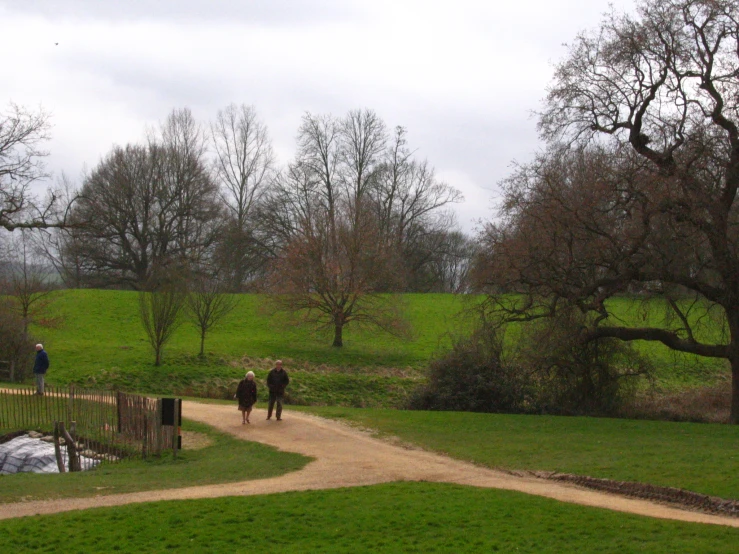 people are walking down the dirt path in a park