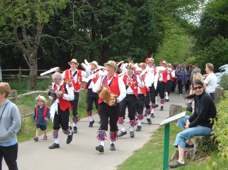 a large band walks down a path wearing matching outfits