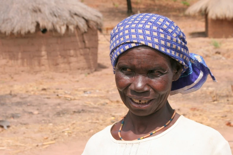 a woman is wearing a blue hat and standing in front of huts