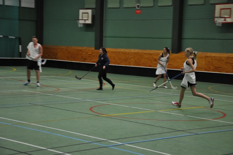 four girls are playing badminton on a hard court