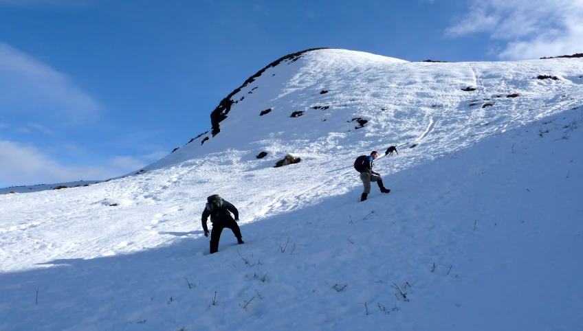 people riding skis down the side of a snow covered slope