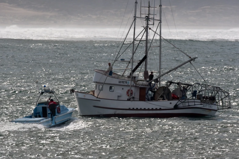 a fishing boat and tug boat moving through the ocean