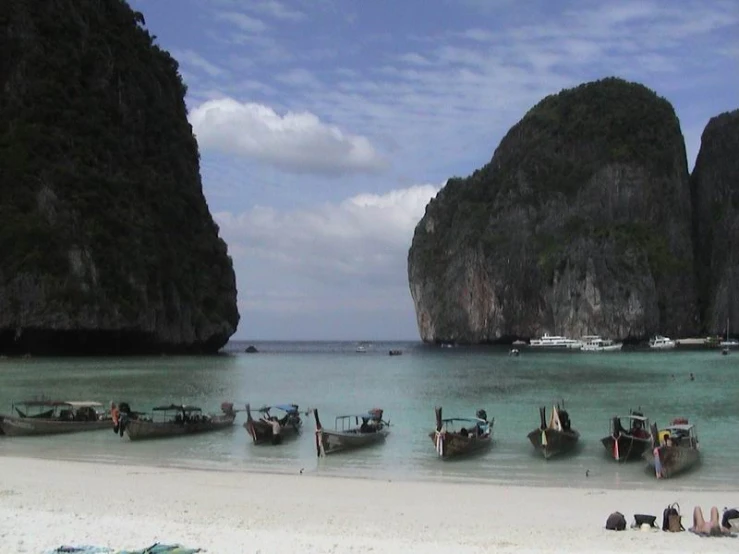 several boats parked on the sand near some mountains