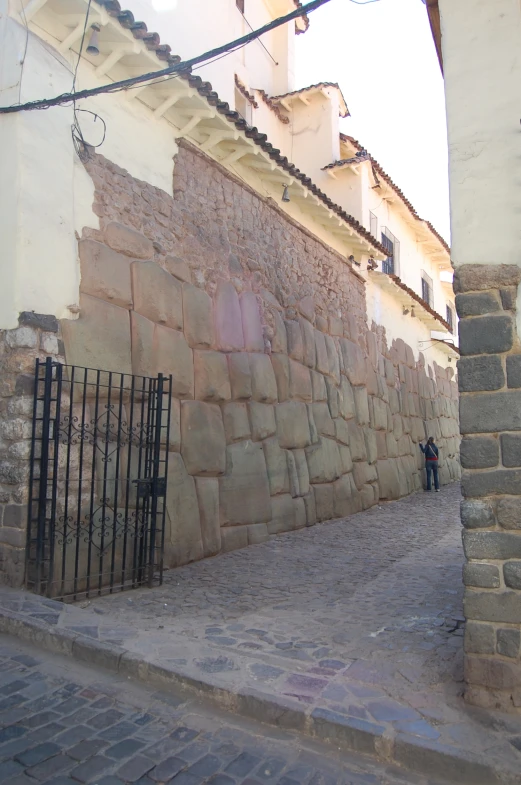 an alley way in a village with an old wall