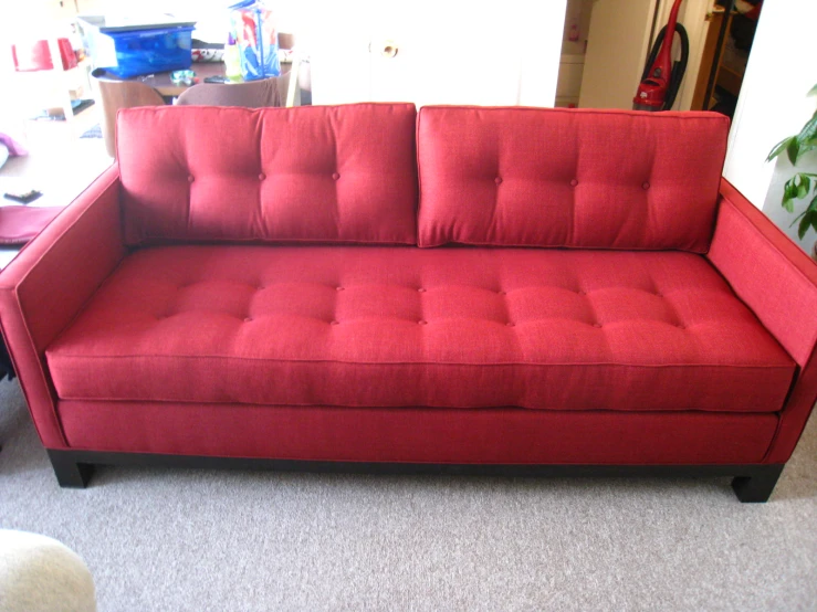 a red love seat is in the corner of a living room