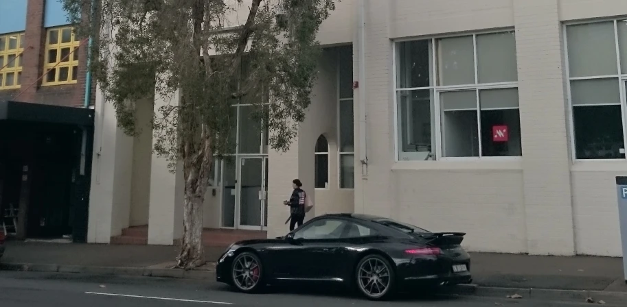 a black porsche parked next to a white building