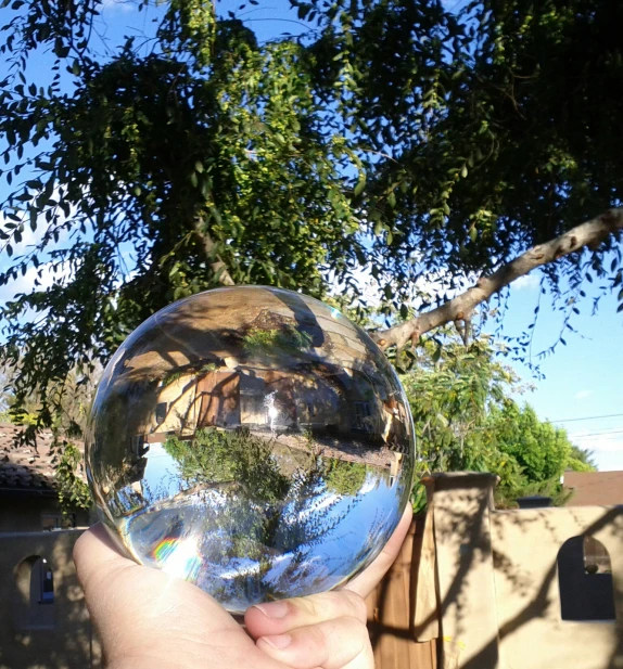 a hand holds a clear glass ball outside