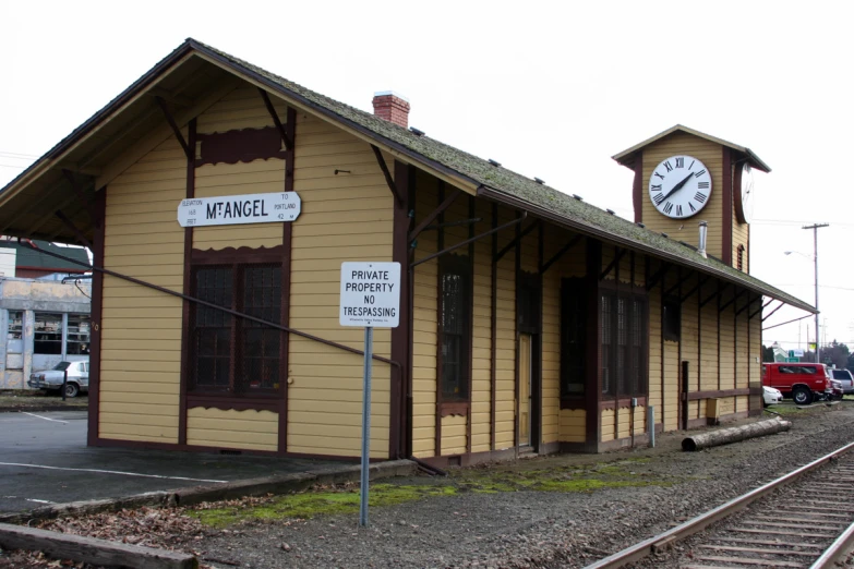 a yellow train station with a clock mounted on it's side