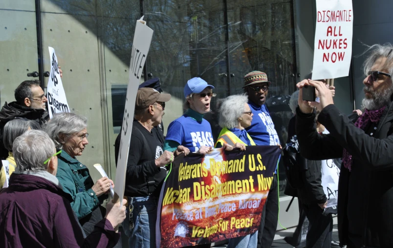 several people are holding a sign and one person is on the phone