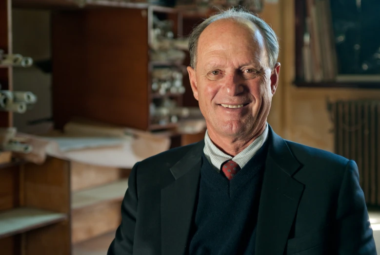 an older gentleman in a suit and tie posing for a portrait