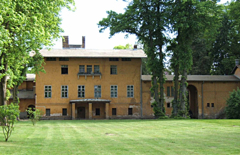 the large yellow house is behind some tall trees