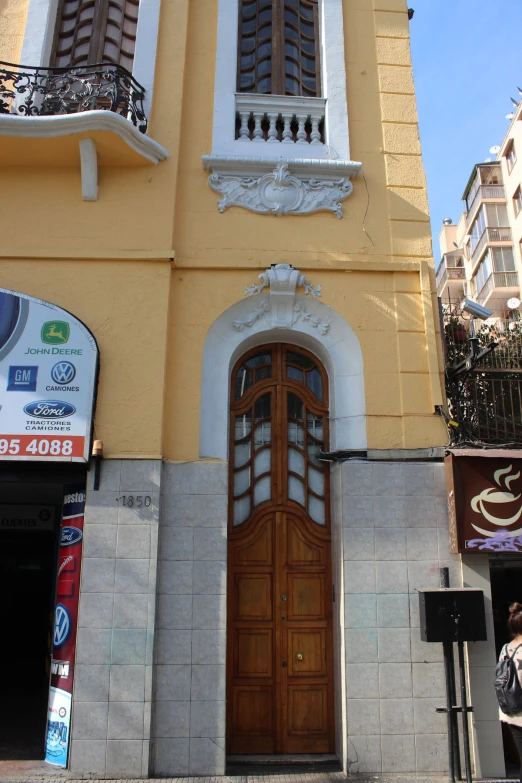 a tall yellow building with a clock above it's door