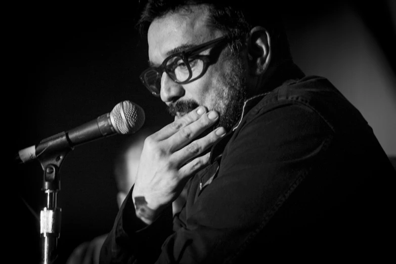 a man wearing glasses with a microphone in front of him