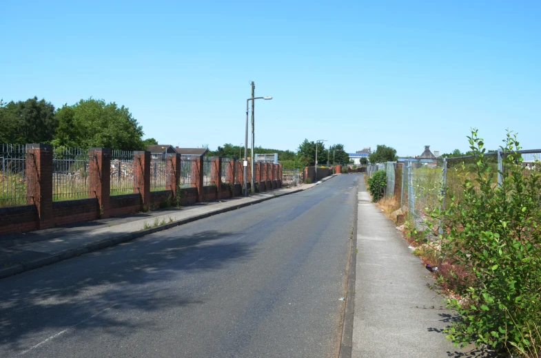 the road by the fence has many small weeds