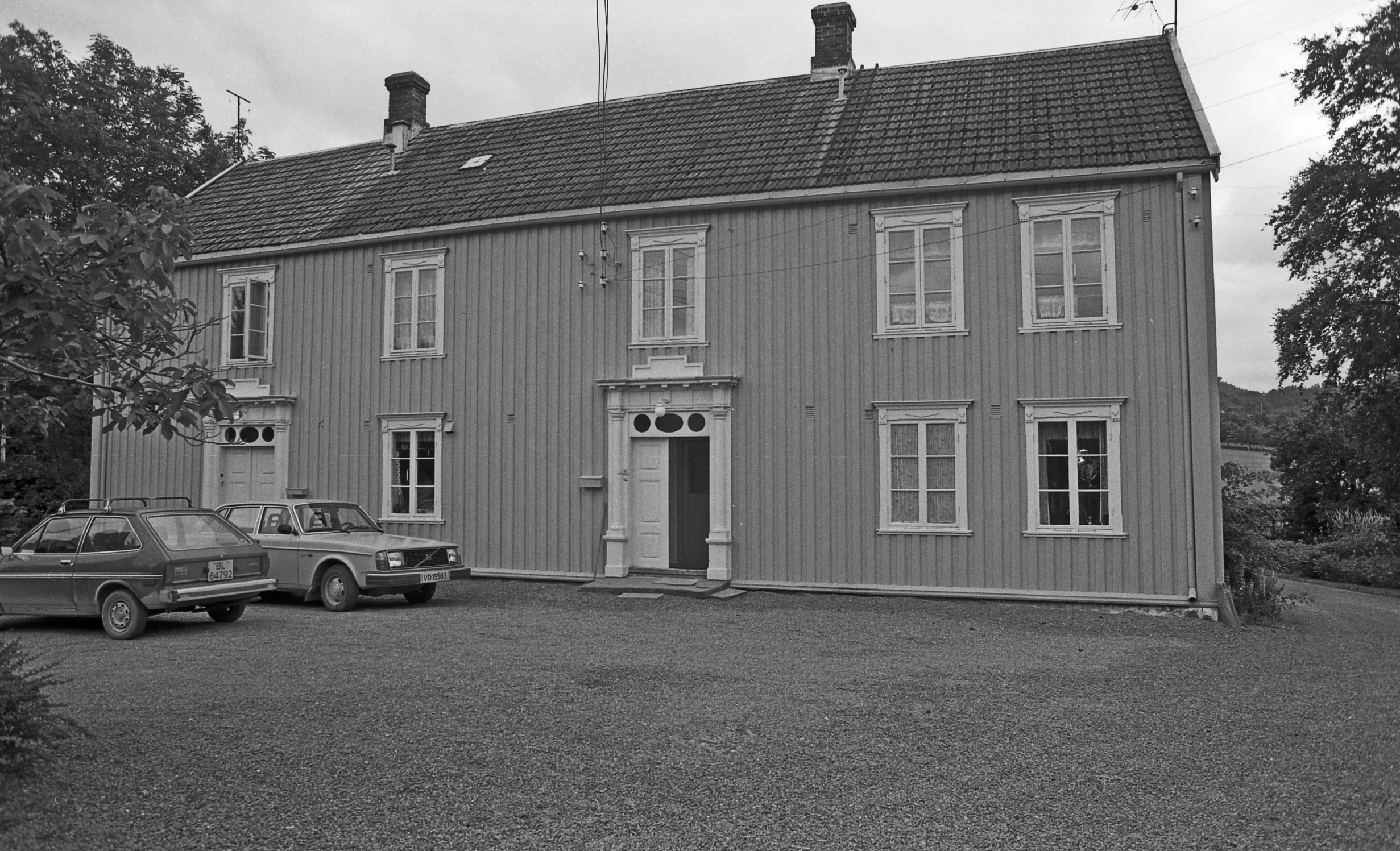 the house is in black and white with a car parked next to it