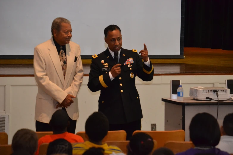 two military officers speaking to children at a ceremony