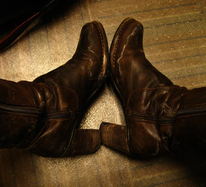 two brown leather boots sit on top of a floor