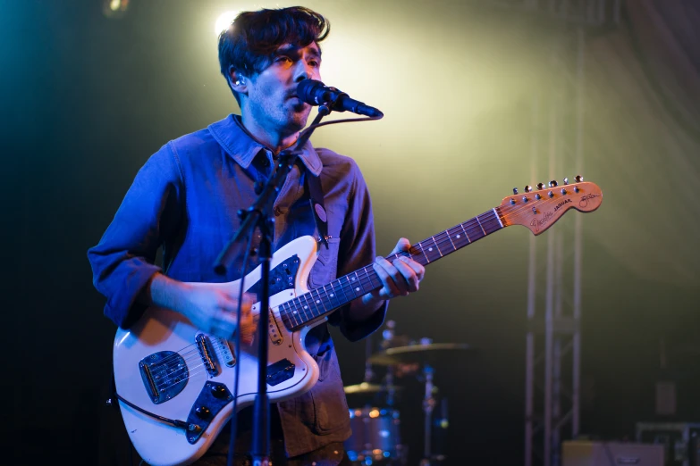 man playing electric guitar in front of microphone