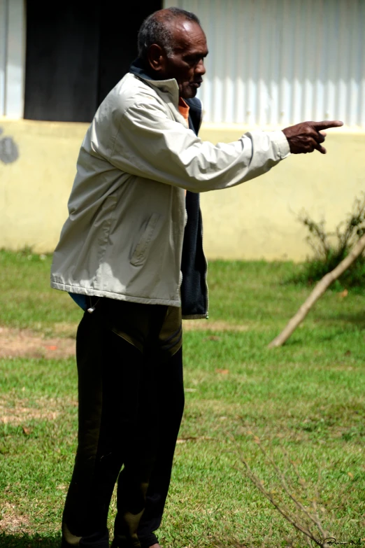 man pointing out a doorway wearing black pants and a white jacket