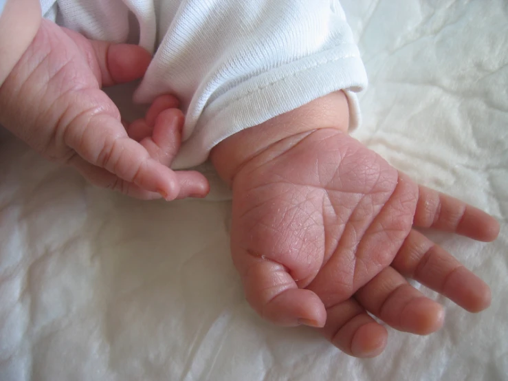 a baby in a white wrap holding his hand out