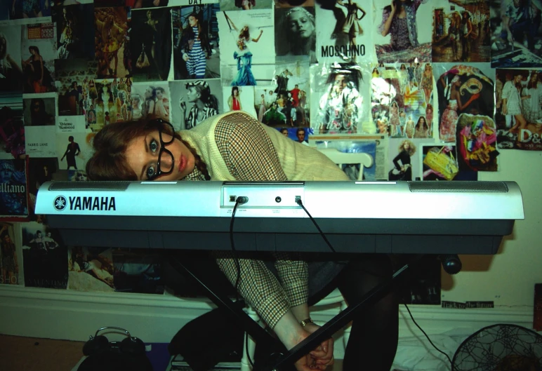 a person wearing glasses, with their face on the keyboard of a keyboard that reads yamaha