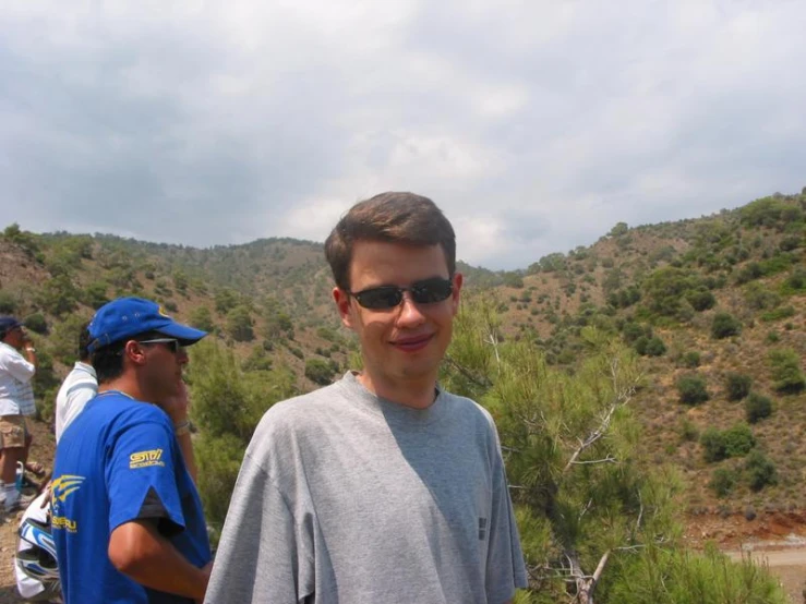 a man stands near another guy near a hill