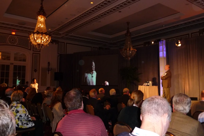 a crowd at a conference listening to a speaker