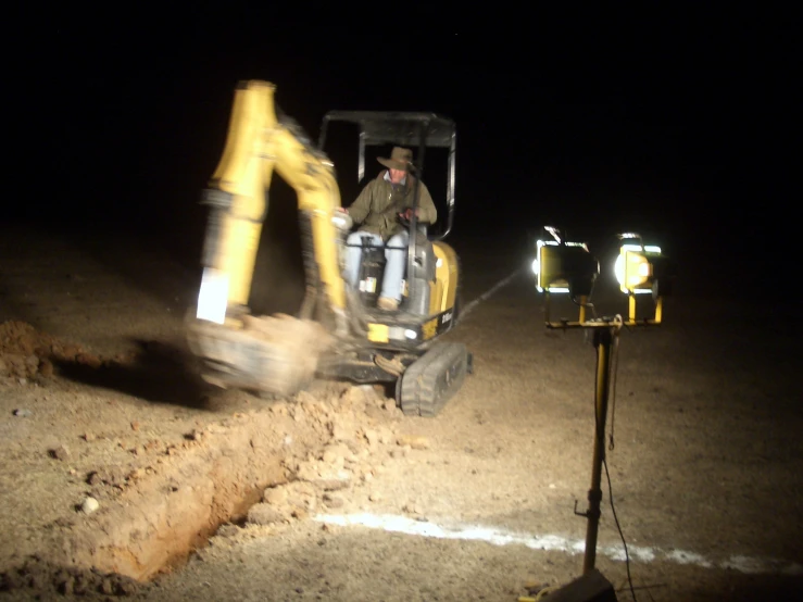 a man driving a bulldozer across a dirt field at night