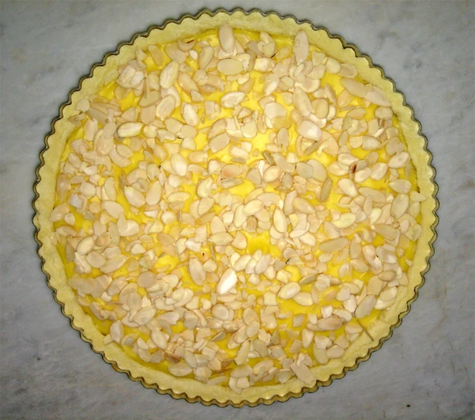 a large pie with almonds sits on a grey table