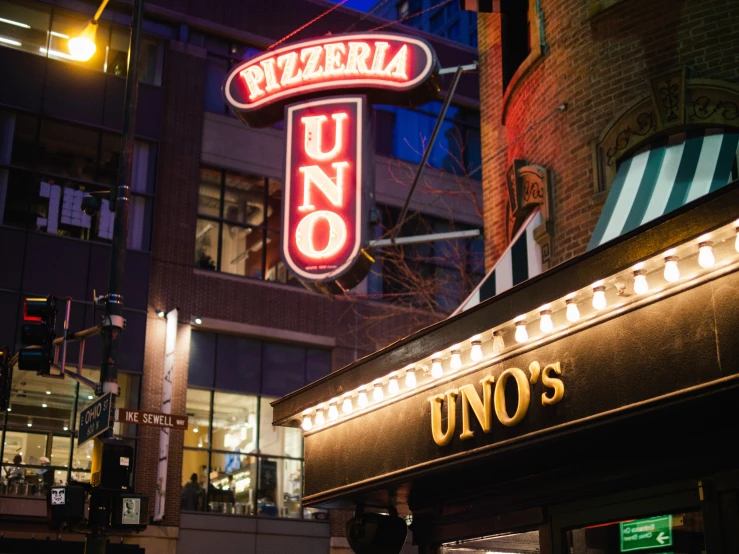 the neon sign for an uno's restaurant is in front of a brick building