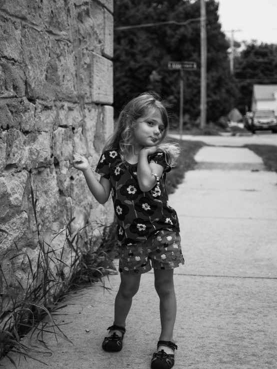 a little girl standing by the wall holding soing