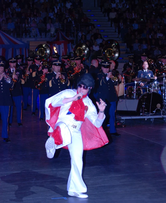 a man wearing white pants is dancing while other people stand in the background