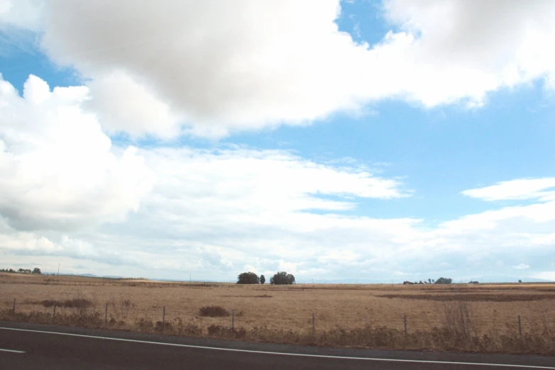 a road on the side of a big open field