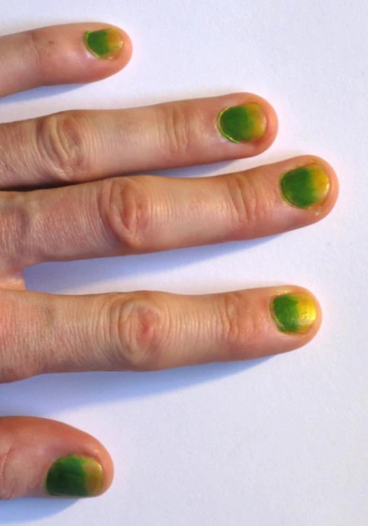 a person has two finger nails with green decorations