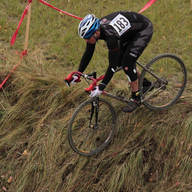 a person riding on the back of a bicycle through tall grass