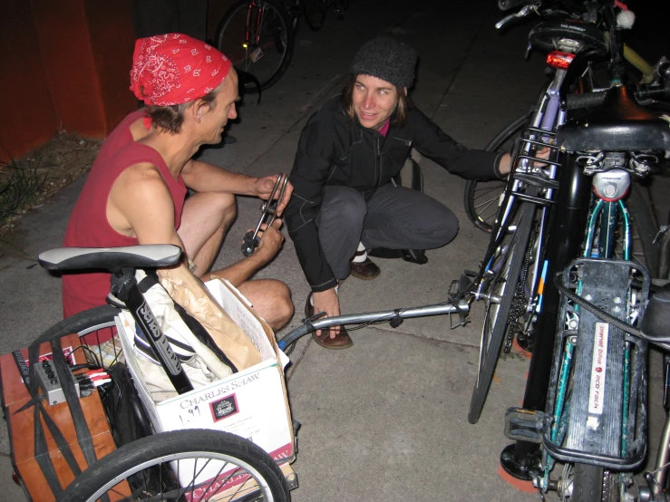 a man sitting down with his friend near bicycles