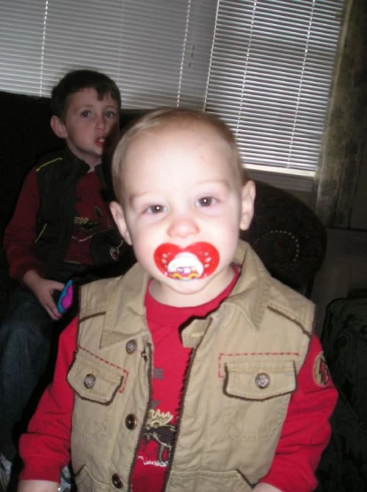 a small child has red teeth and brown jacket on