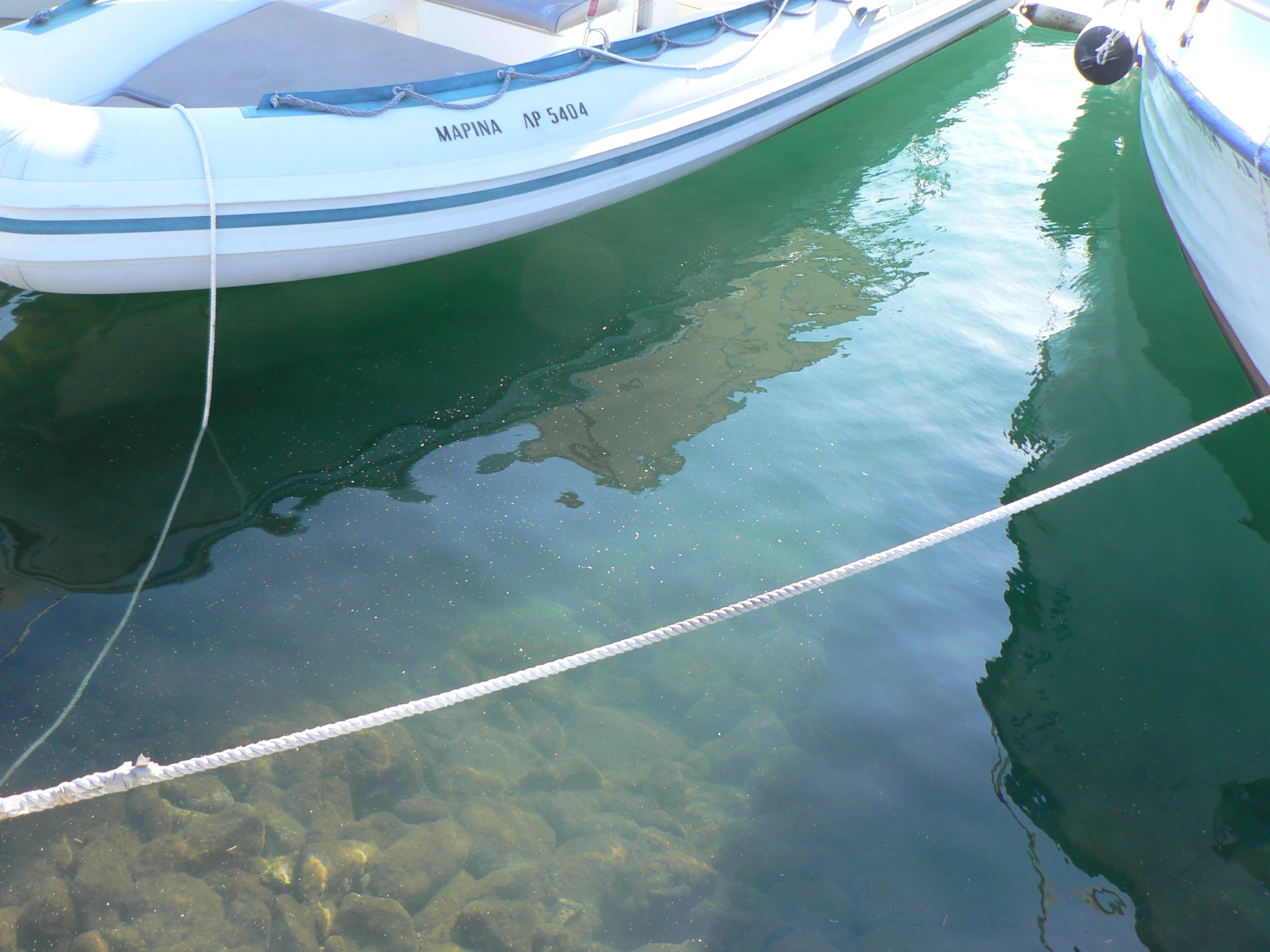 three boats docked at the water with one tied up