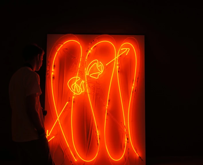 a man standing in front of a neon art display
