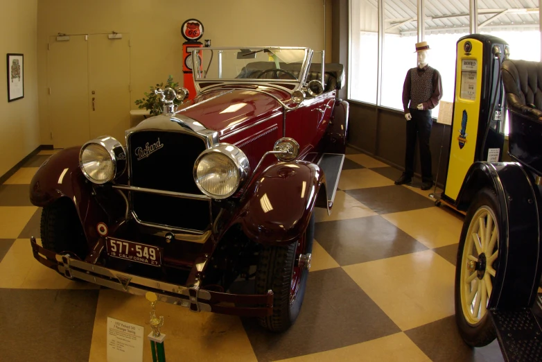 antique cars and men in uniforms standing inside an old building