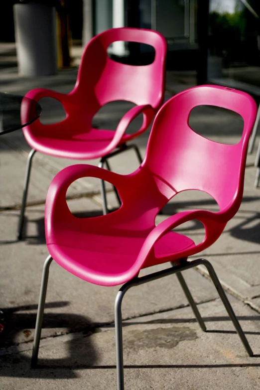 pink chairs sit in a row on a sidewalk