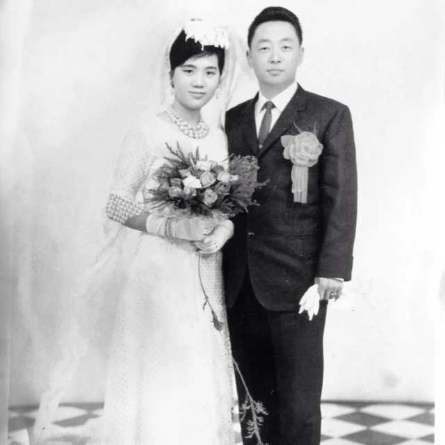 a black and white po shows a woman in a wedding dress holding flowers next to a man in a suit and tie