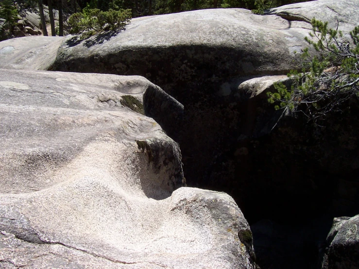 a natural rock formation with various sized boulders, with trees in the background
