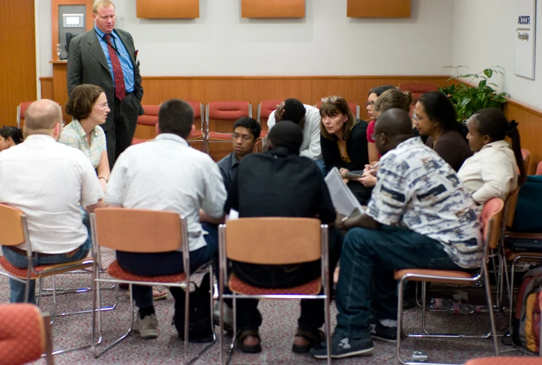 a group of people sitting in chairs with laptops